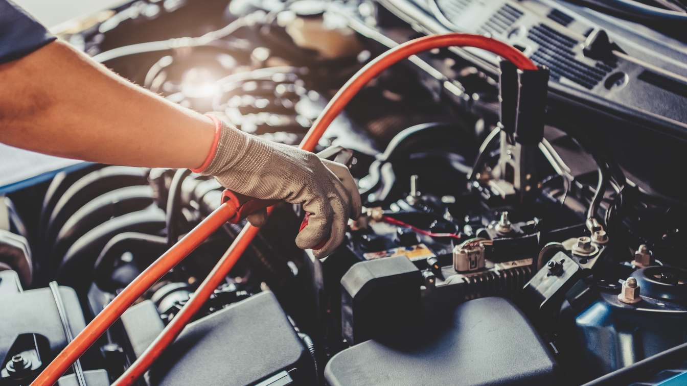 Technician connecting test leads to a vehicle battery